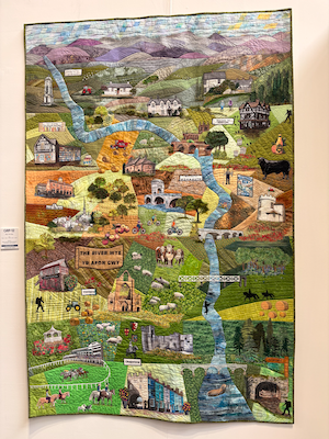 a quilted pictographic map of the river wye, this was made by a group called trease l, sylvia l, fiona b, linda t, linda r
