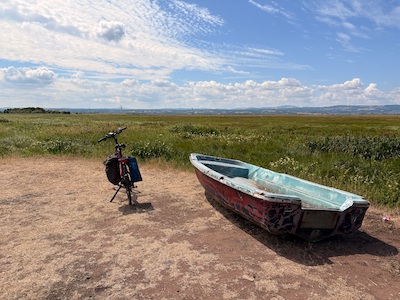My bike with a boat on sunny marshland with no sea in sight.