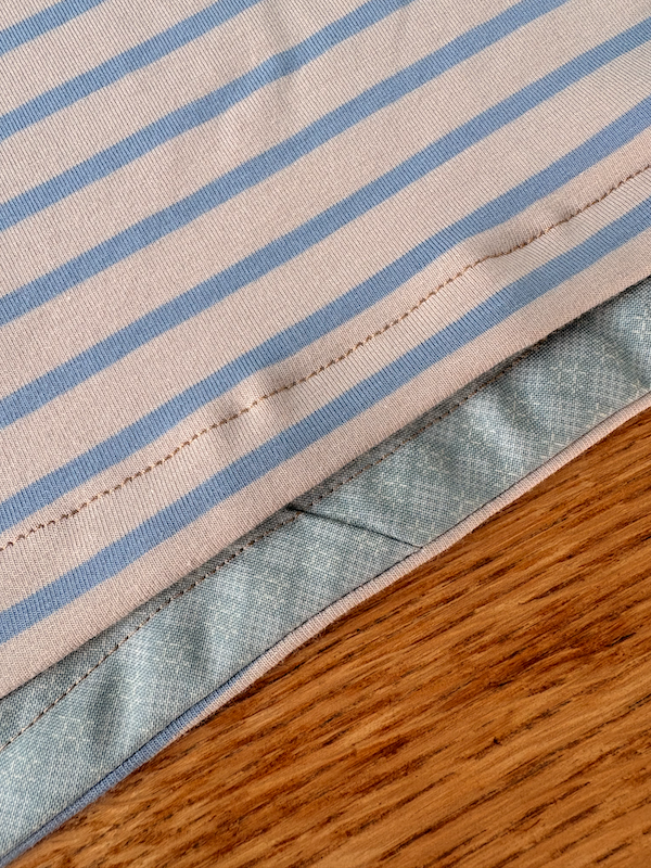 close up of the hem of a blue/beige stripy t-shirt showing the pale blue bias binding hem